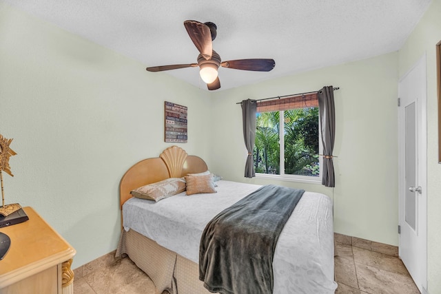 bedroom with ceiling fan and a textured ceiling
