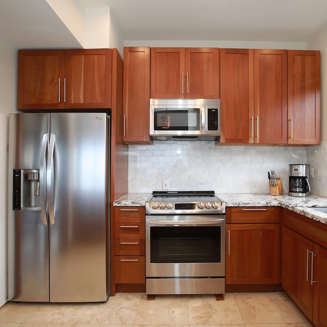 kitchen featuring backsplash, light tile flooring, stainless steel appliances, and light stone countertops