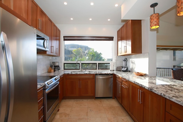 kitchen featuring appliances with stainless steel finishes, sink, light stone counters, tasteful backsplash, and pendant lighting