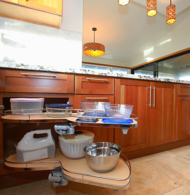 kitchen with light tile floors, light stone countertops, and pendant lighting