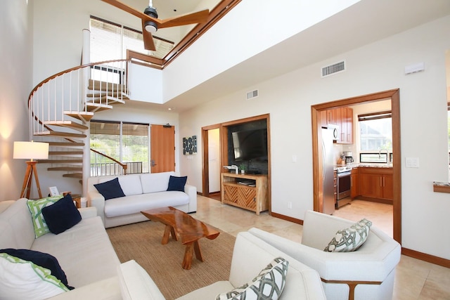 tiled living room featuring sink, a towering ceiling, and a wealth of natural light