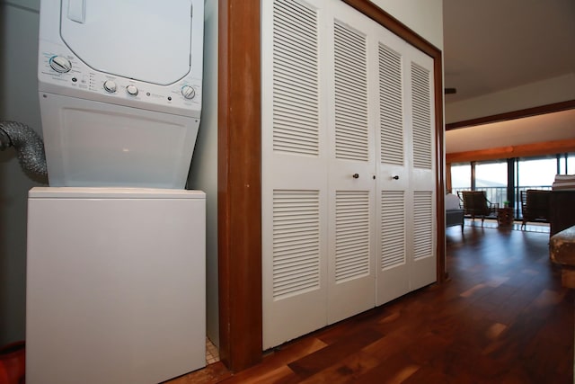 washroom featuring stacked washer and clothes dryer and dark hardwood / wood-style flooring