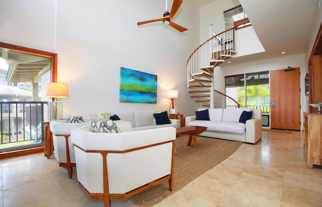 tiled living room with ceiling fan, a high ceiling, and plenty of natural light