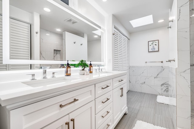 bathroom with walk in shower, tile walls, vanity, and a skylight