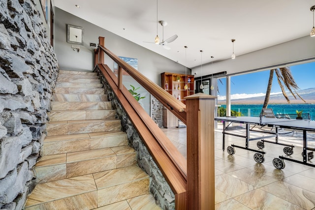 stairs with a water view, ceiling fan, and lofted ceiling