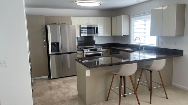 kitchen featuring a breakfast bar, dark stone countertops, a peninsula, stainless steel appliances, and a sink