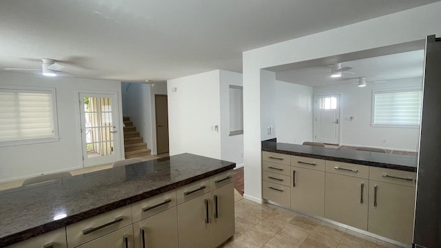 kitchen with plenty of natural light, open floor plan, ceiling fan, and dark stone countertops