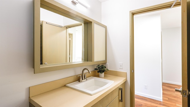 bathroom with wood finished floors, vanity, and baseboards