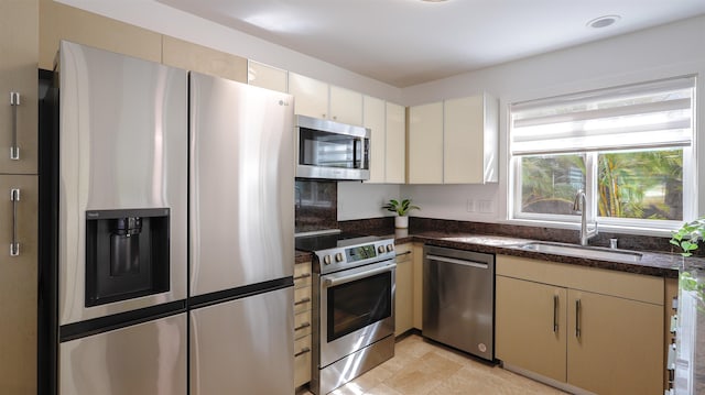 kitchen featuring stainless steel appliances, a sink, and dark stone countertops