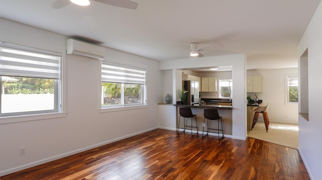 kitchen featuring dark wood-style floors, a wall mounted air conditioner, ceiling fan, and stainless steel fridge