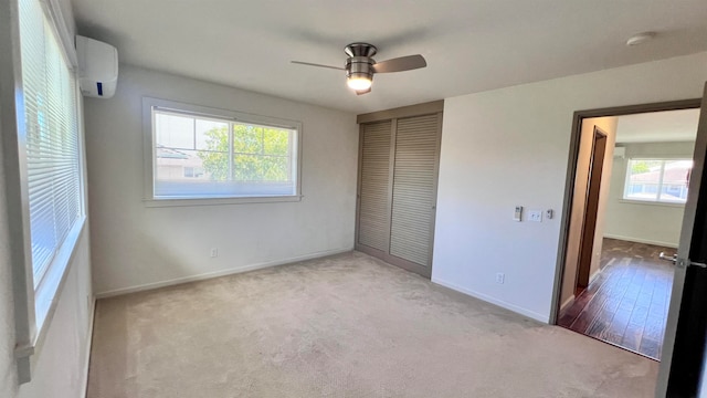 unfurnished bedroom featuring carpet, multiple windows, a wall unit AC, and a closet