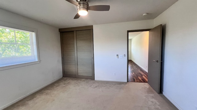 unfurnished bedroom featuring ceiling fan, light carpet, and a closet