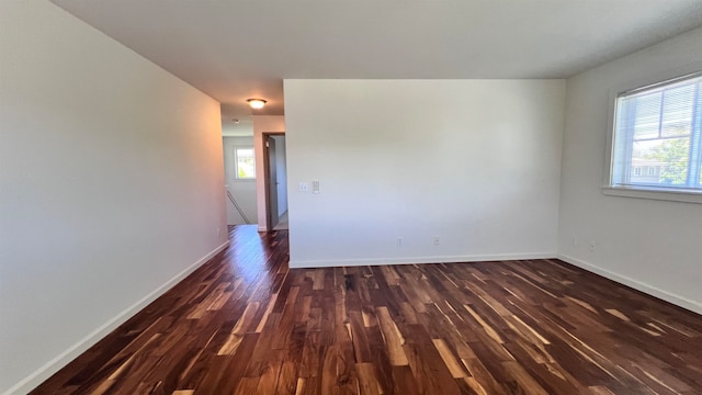 spare room featuring dark hardwood / wood-style flooring and a healthy amount of sunlight