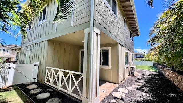 view of property exterior with central air condition unit, a fenced backyard, a gate, and board and batten siding