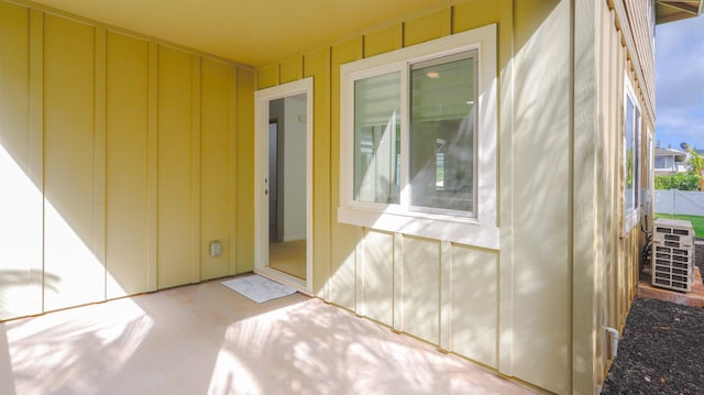 entrance to property featuring a patio, board and batten siding, and fence