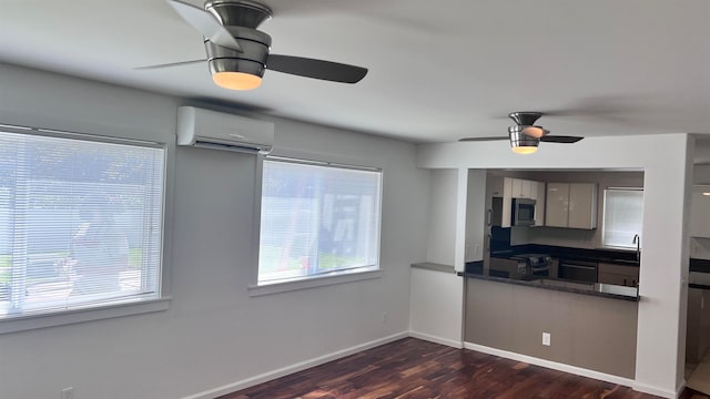 kitchen with stainless steel appliances, dark hardwood / wood-style flooring, sink, dark stone countertops, and a wall mounted air conditioner