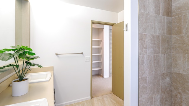 full bathroom featuring a tile shower and double vanity