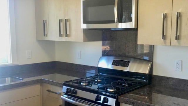 kitchen featuring dark stone counters, light brown cabinets, decorative backsplash, and appliances with stainless steel finishes