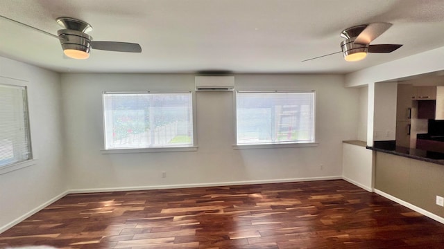 empty room with a wall unit AC, dark hardwood / wood-style floors, and ceiling fan