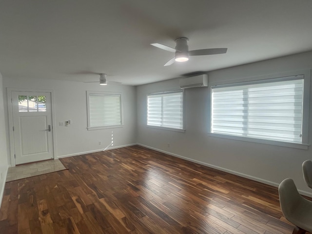 interior space with a wall unit AC, ceiling fan, baseboards, and dark wood-type flooring