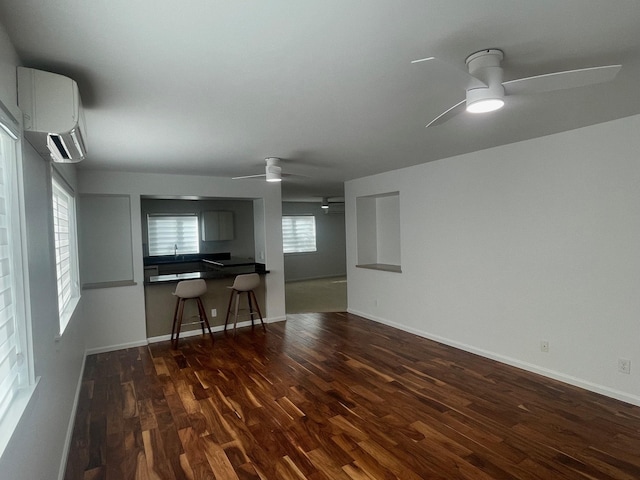 unfurnished living room with dark wood-style floors, a ceiling fan, baseboards, and a wall mounted AC