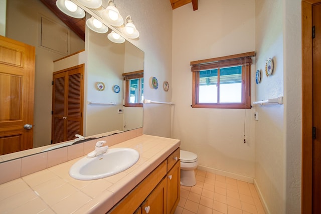 bathroom with toilet, tile patterned floors, vanity, and beamed ceiling