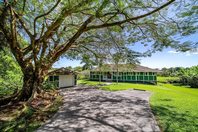 view of front of house with a front lawn, a garage, a sunroom, and an outbuilding