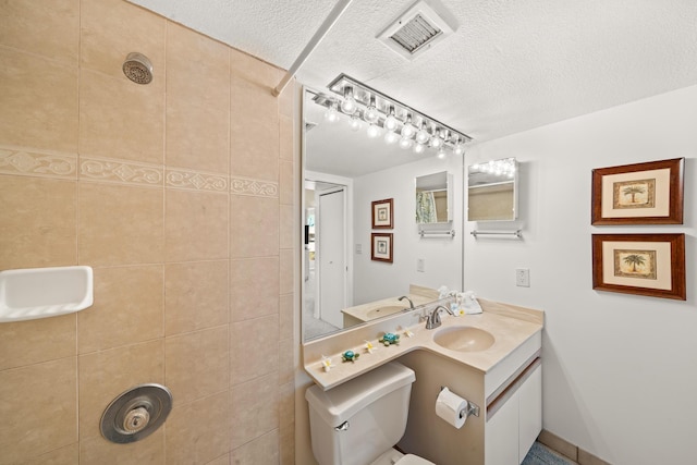 full bath with visible vents, vanity, toilet, a textured ceiling, and a tile shower