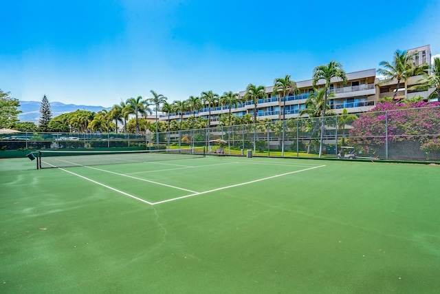 view of tennis court with a mountain view and fence