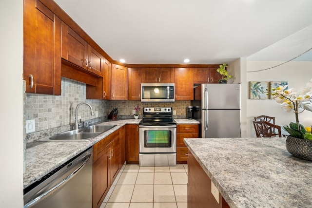 kitchen with brown cabinets, light tile patterned flooring, a sink, stainless steel appliances, and decorative backsplash