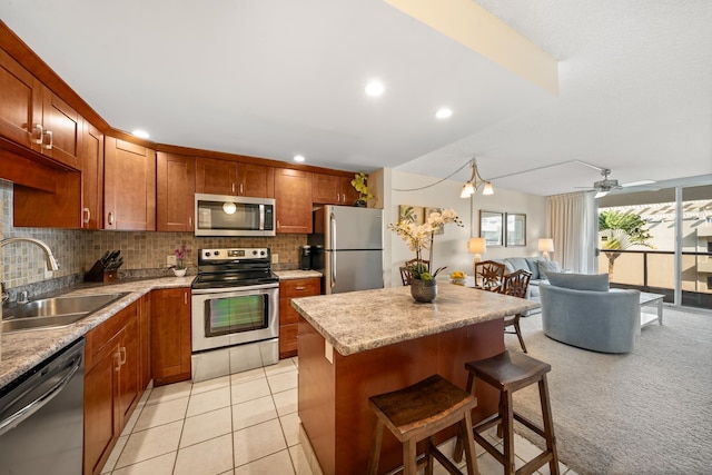 kitchen featuring decorative backsplash, open floor plan, a center island, a sink, and stainless steel appliances
