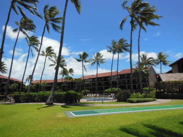 view of property's community with a lawn, fence, a pool, and shuffleboard