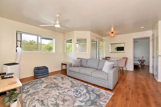 living area featuring wood finished floors, baseboards, and ceiling fan