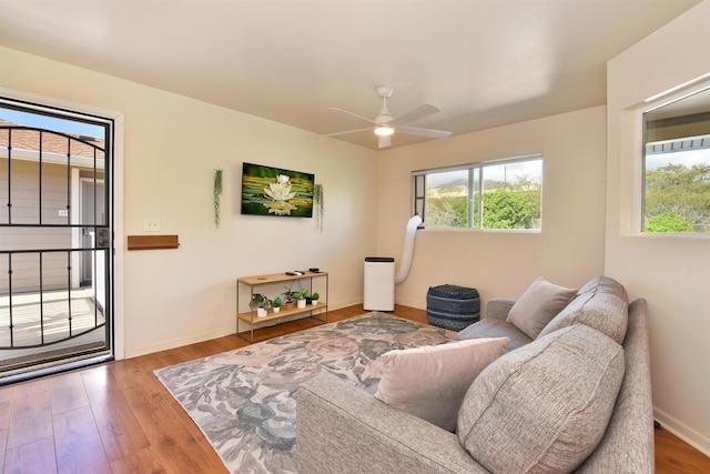 living room with wood finished floors, baseboards, and ceiling fan