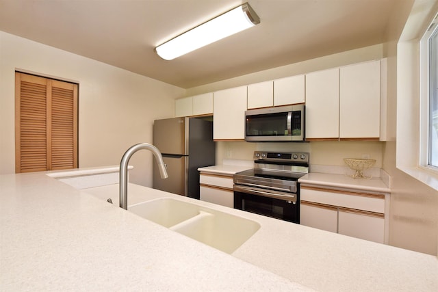 kitchen featuring white cabinets, appliances with stainless steel finishes, light countertops, and a sink