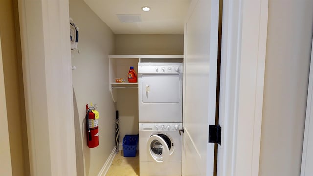 clothes washing area featuring stacked washer and clothes dryer, laundry area, and baseboards
