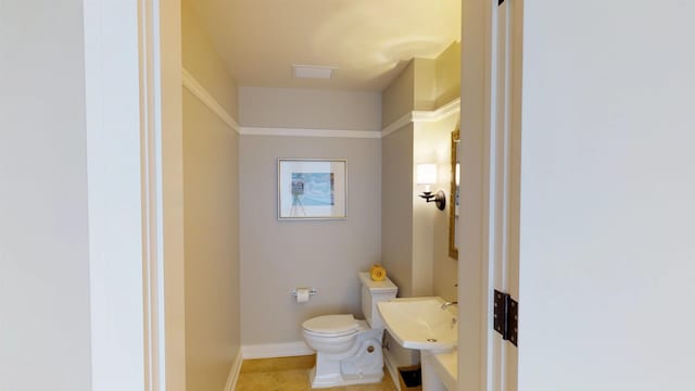 half bathroom with tile patterned floors, a sink, toilet, and baseboards