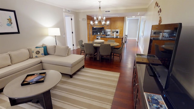 living room with dark wood-style floors, baseboards, an inviting chandelier, and crown molding
