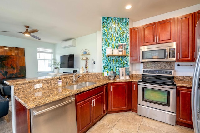 kitchen featuring open floor plan, a wall unit AC, a peninsula, stainless steel appliances, and a sink