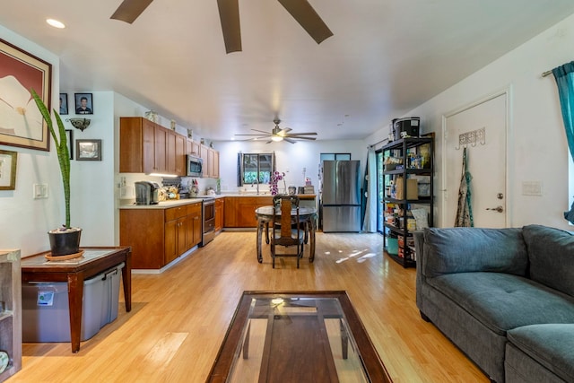 living room with ceiling fan, sink, and light wood-type flooring