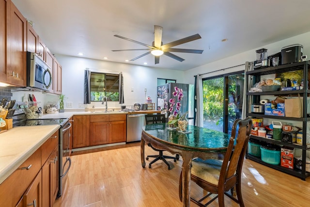 kitchen with appliances with stainless steel finishes, sink, ceiling fan, and light hardwood / wood-style flooring