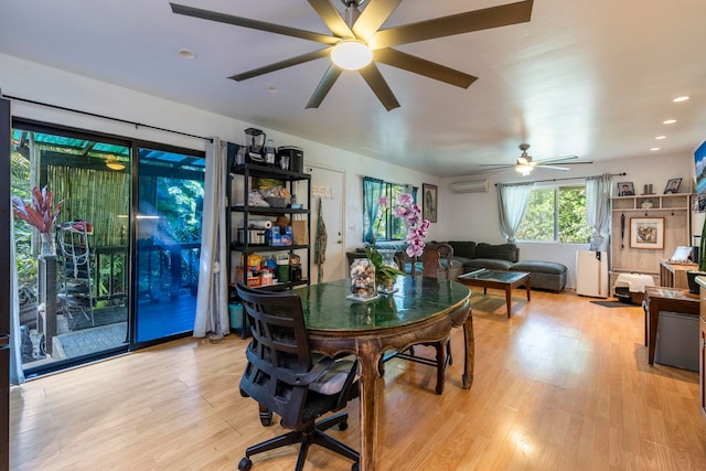 dining area with light wood-type flooring, ceiling fan, and a wall mounted air conditioner