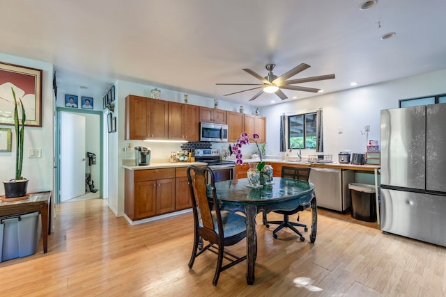 kitchen with backsplash, ceiling fan, light hardwood / wood-style flooring, and appliances with stainless steel finishes