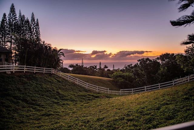 yard at dusk featuring a rural view