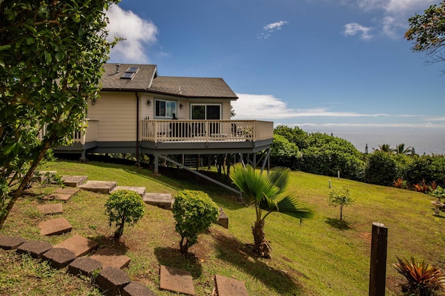 rear view of house featuring a wooden deck and a lawn