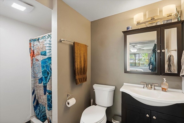 bathroom with vanity, ceiling fan, toilet, and curtained shower