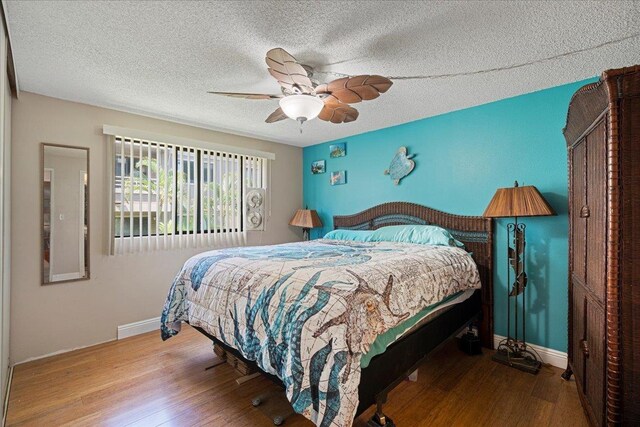 bedroom with hardwood / wood-style flooring, ceiling fan, and a textured ceiling