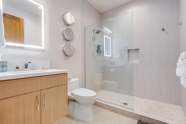 bathroom with tile patterned floors, a tile shower, vanity, and toilet