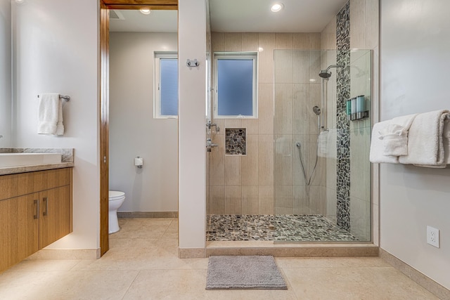 bathroom featuring toilet, a tile shower, vanity, and tile patterned floors