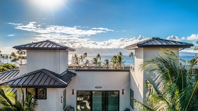 rear view of house featuring a balcony and a water view